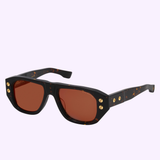 Dita Sunglasses RHYTHX DTS741-A-03 Limited Edition: Black oversized sculptural navigator frames with brown-tinted lenses, gold rivet details, and subtle tortoiseshell patterning, shown against a light purple background.