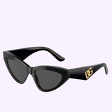 The Dolce&Gabbana Sunglasses 0DG4439 501/87 are black women’s cat-eye sunglasses featuring dark lenses and a gold DG logo on the arms, showcased against a light purple background. These stylish sunglasses bring an elegant touch to any outfit.