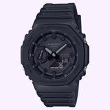 The G-Shock Watches GA2100-1A1 2100 Series (UPC: 889232241630) is a black rugged timepiece combining digital and analog displays, celebrated for its shock resistance and durable construction, with multiple side buttons, pictured against a light background.