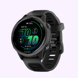 A black Garmin Watches Forerunner® 570 - 42mm (010-02970-00) smartwatch with a round AMOLED display and aluminum bezel displays time, date, battery, steps, heart rate, and activity icons on a light purple background.