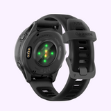 The Garmin Watches Forerunner® 570 - 42mm (010-02970-00) in black displays glowing green rear sensor lights, a silicone band with RUN engraved on the loop, and a lightweight aluminum bezel.