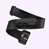 A black Garmin Watches HRM 600 010-13383-01 heart rate monitor strap with central sensor module and adjustment buckle is shown on a light background, featuring a small instruction tag—compatible with Garmin Watches.