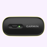 A black Garmin Watches HRM 600 010-13383-01 device with a yellow border, power switch, and green indicator light is shown on a light purple background.