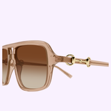 Close-up of the Gucci Sunglasses GG2052S-010 55 by Gucci Sunglasses, featuring stylish oversized square frames in transparent brown, brown gradient lenses, and elegant gold accents on the temples—an exquisite statement piece for luxury fashion lovers—displayed against a light purple background.
