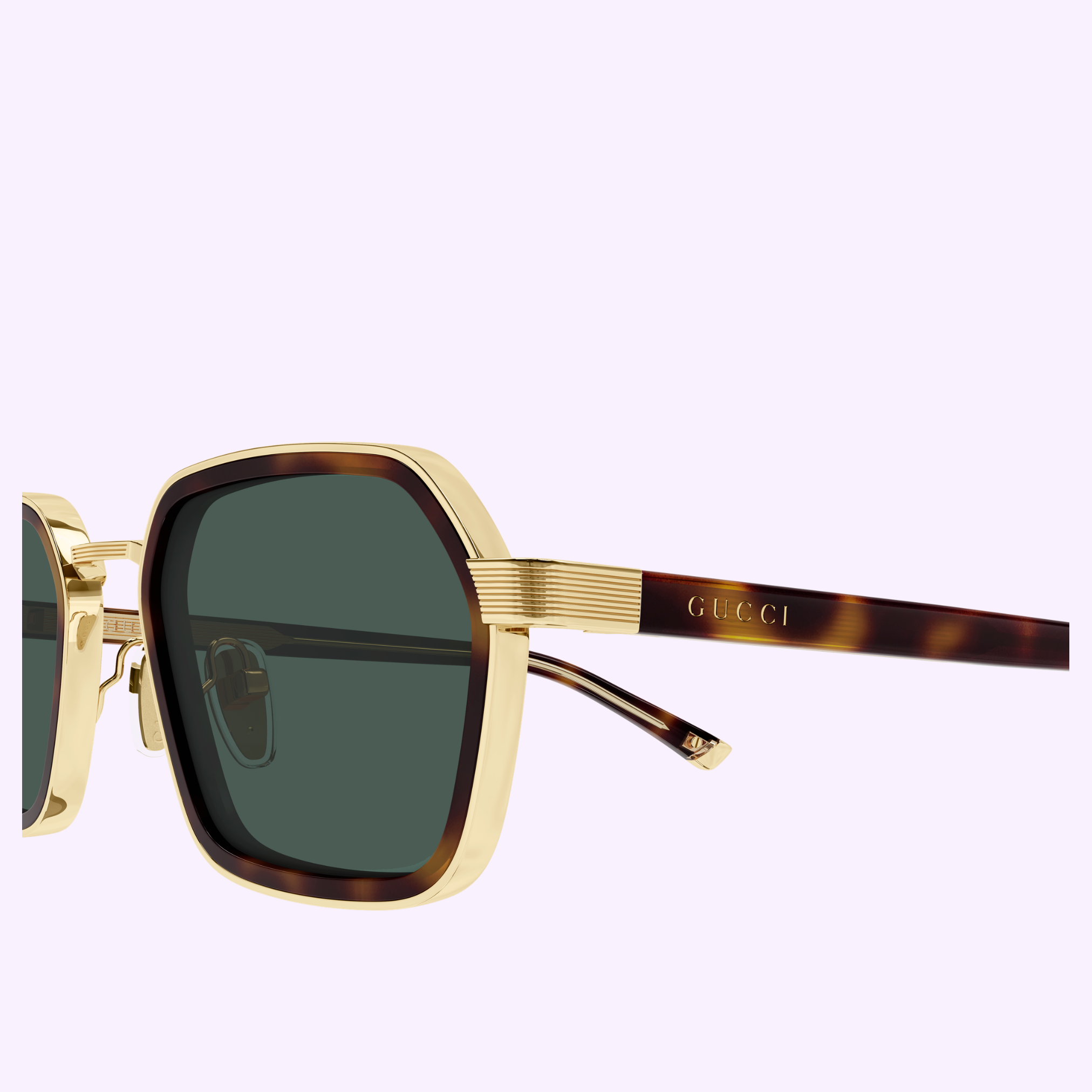 Close-up of Gucci Sunglasses GG2074S-003 51 featuring gold and tortoiseshell frames with dark green lenses and the GUCCI logo engraved on the temple, set against a light purple background—a striking example of contemporary luxury eyewear.