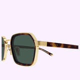 Close-up of Gucci Sunglasses GG2074S-003 51 featuring gold and tortoiseshell frames with dark green lenses and the GUCCI logo engraved on the temple, set against a light purple background—a striking example of contemporary luxury eyewear.