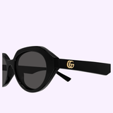 Close-up of Gucci Sunglasses GG2178S-001 53 featuring a sleek black frame, round dark lenses, and the iconic gold GG logo on the temple, set against a light purple background—a striking accessory that embodies luxury fashion and modern style.