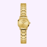 The Guess Watches GW0244L2 Gold Tone Stainless Steel Watch features a round face, minimalist dial with Swarovski crystal markers at 12, 3, 6, and 9 o’clock, and a linked bracelet—shown on a light purple background.