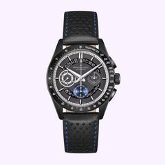 The Hamilton Jazzmaster Performer Autochrono 42mm H36646780 by Hamilton Watches features a black case, perforated leather strap with blue stitching, tachymeter bezel, and three subdials on a dark grey dial, shown on a light purple background.