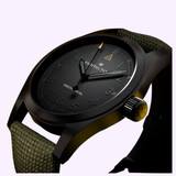A detailed view of the Hamilton Watches Call of Duty: Modern Warfare 4 KHAKI FIELD H69469930 SPECIAL EDITION highlights its black dial, luminous hands, dark green fabric strap, yellow crown accent, and distinctive yellow triangle at the 12 o’clock position—a signature piece from Hamilton Watches featured in Call of Duty: Modern Warfare 4.