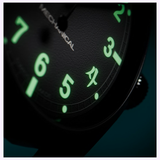 Close-up of the Hamilton Watches Call of Duty: Modern Warfare 4 KHAKI FIELD H69469930 SPECIAL EDITION watch face in darkness, highlighting the glowing green numerals—3, 4, 5, and 6—and a symbol between 4 and 5. The partially visible word “MECHANICAL” near the center evokes the look of both the iconic H69469930 model and its in-game counterpart from Call of Duty: Modern Warfare 4 by Hamilton Watches.