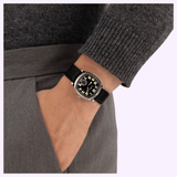 A vintage-style Hamilton Watches H36129730 American Classic Cushion Mechanical watch with a black dial, Arabic numerals, and a black leather strap, worn on a person’s wrist.