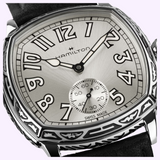 Hamilton Watches H36149710 American Classic Cushion Mechanical, an Art Deco style cushion-shaped watch with a silver dial, bold black numerals, an engraved metal case, and a black strap.