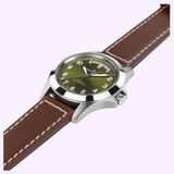 Hamilton Watches H64475560 Khaki Field King Day-Date automatic watch with a green dial, silver-tone case, and brown leather strap featuring a day and date window at the twelve o’clock position.