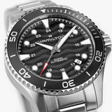 Close-up of the Hamilton Watches H82415130 Khaki Navy Scuba Auto 40mm by Hamilton Watches, featuring a black wavy textured dial, bold hour markers, red-tipped second hand, and a stainless steel bracelet. The sporty bezel displays large numerals for easy reading.