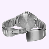 The Hamilton Watches H82415130 Khaki Navy Scuba Auto 40mm, a stainless steel automatic dive watch from Hamilton Watches, is shown with its clasp open, revealing the engraved case back and metal bracelet set against a light purple background.