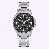 A Hamilton Watches H82415130 Khaki Navy Scuba Auto 40mm wristwatch by Hamilton Watches, featuring a stainless steel case, round black dial with silver hour markers and a date window, and a silver bracelet, displayed against a light purple background.
