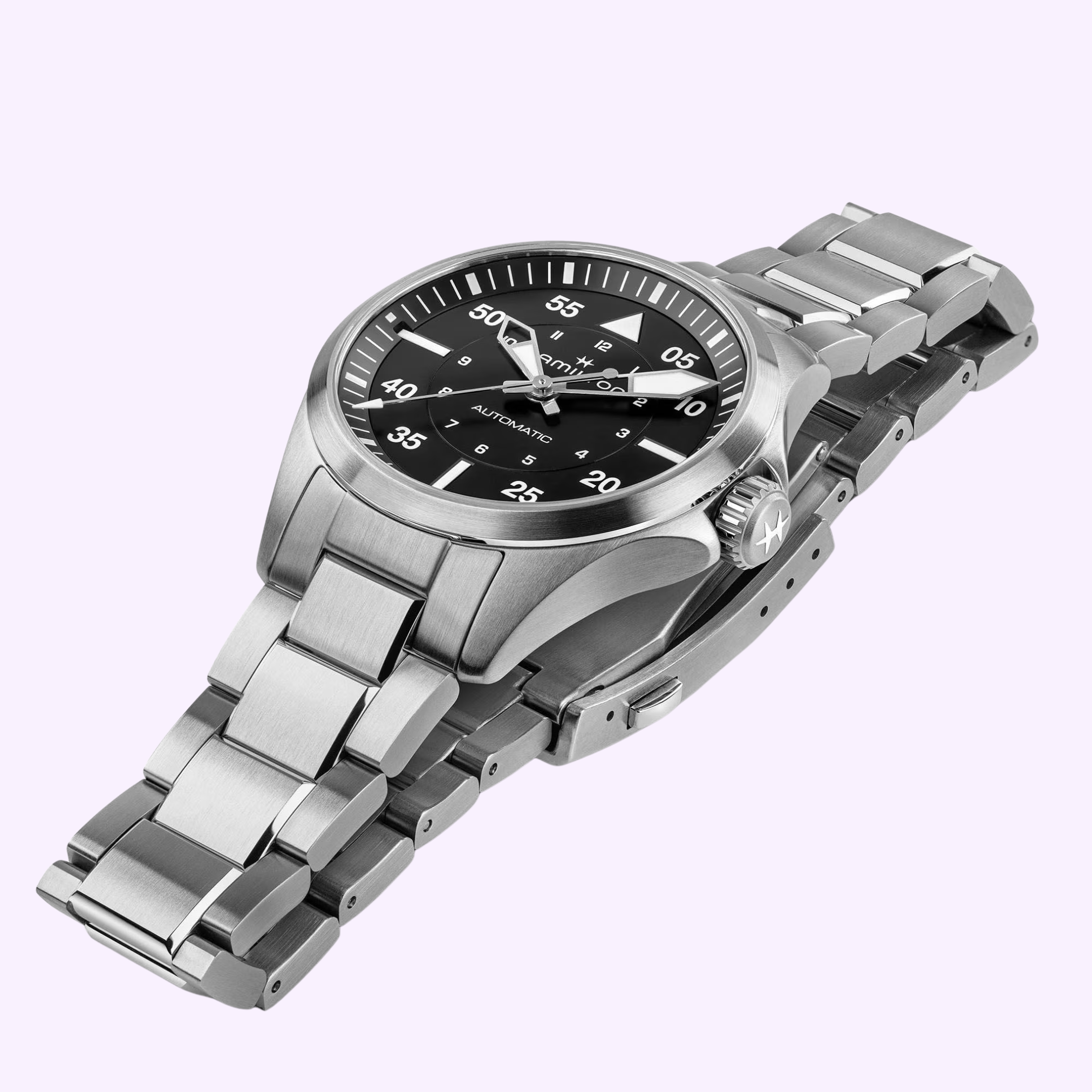The Hamilton Watches Khaki Aviation Pilot Auto H76215130 features a stainless steel case, black dial with white numerals, metal link bracelet, and classic 36mm design, shown angled on a light purple background.