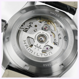 Close-up of the Hamilton Watches Khaki Field Murph 38mm H70405740’s stainless steel case back, showcasing its automatic movement and detailed internal gears. The engraving features WATER RESISTANT, SWISS MADE, and TWENTY-FIVE 25 JEWELS.
