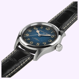 The Hamilton Watches Khaki Field Murph 38mm H70405740 features a textured blue dial, gold numerals, and a black leather strap with white stitching. This automatic timepiece from Hamilton Watches is elegantly displayed at an angle on a light background.