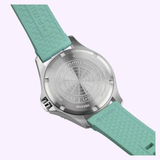 Back view of the Hamilton Watches Khaki Navy Scuba 40mm H82415331, silver case with engraved details and a mint green textured rubber strap, shown against a light purple background.