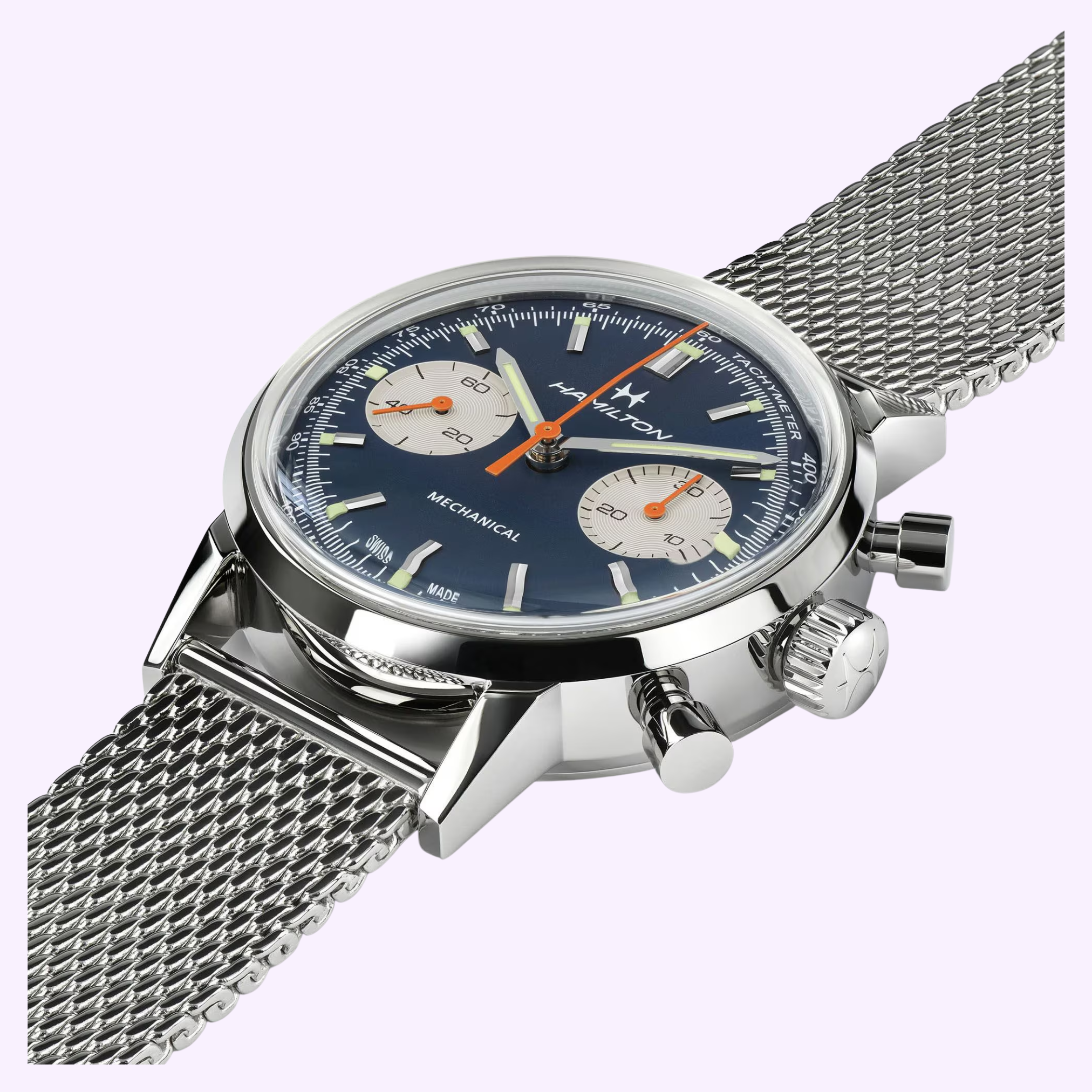 A close-up of the Hamilton Watches American Classic Intra-matic Chronograph H38429541 with a blue dial, two subdials, mesh strap, and bold push-buttons and crown, set against a light purple background.
