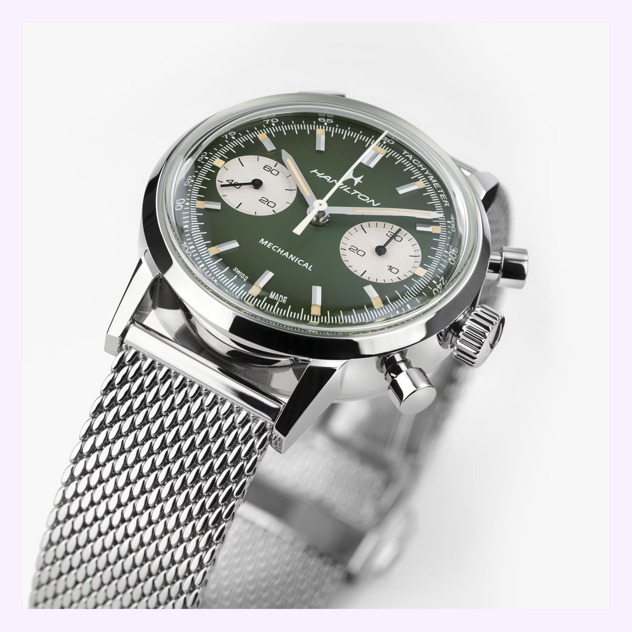 A close-up of the Hamilton Watches American Classic Intra-matic Chronograph H38429861 shows its green dial, two subdials, silver hour markers, and a silver mesh strap against a white background, capturing timeless elegance.