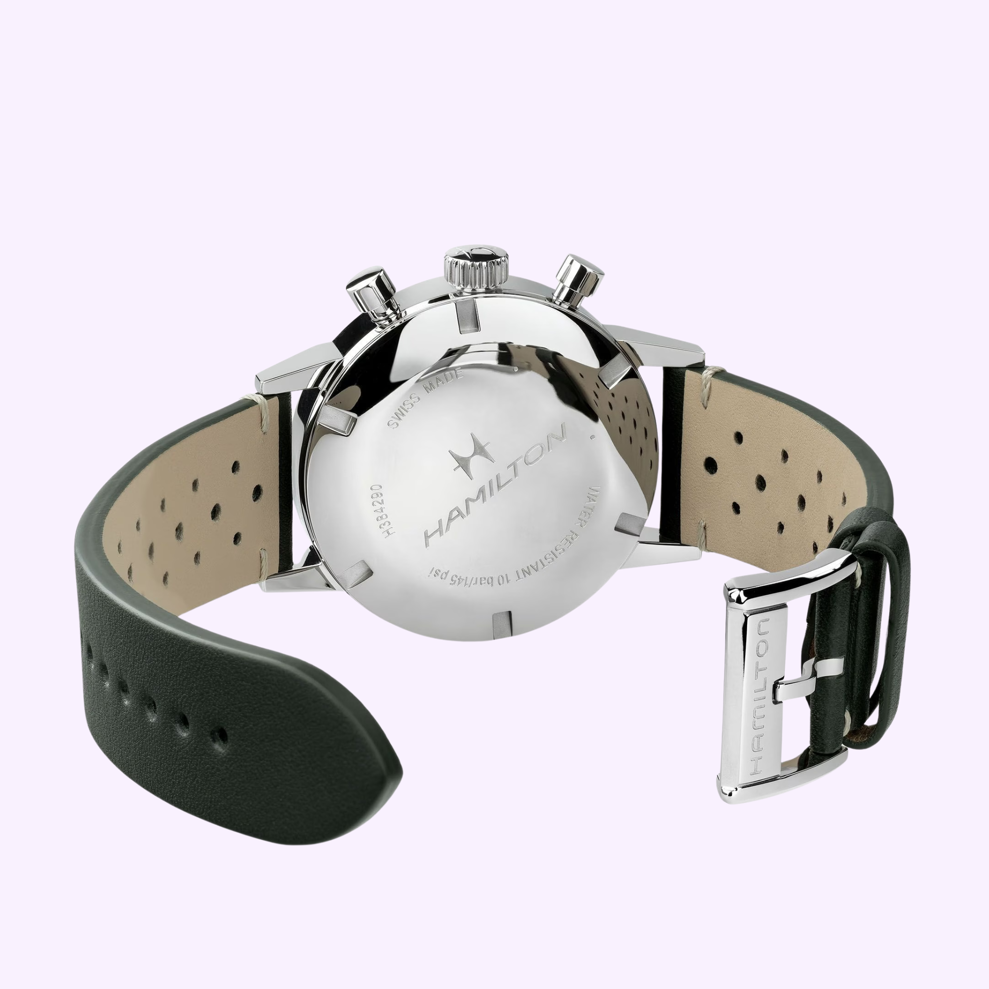 A close-up of the back of a Hamilton Watches American Classic Intra-matic Chronograph H38429861 in silver, featuring a black perforated leather strap and engraved logo, displayed on a light purple background.