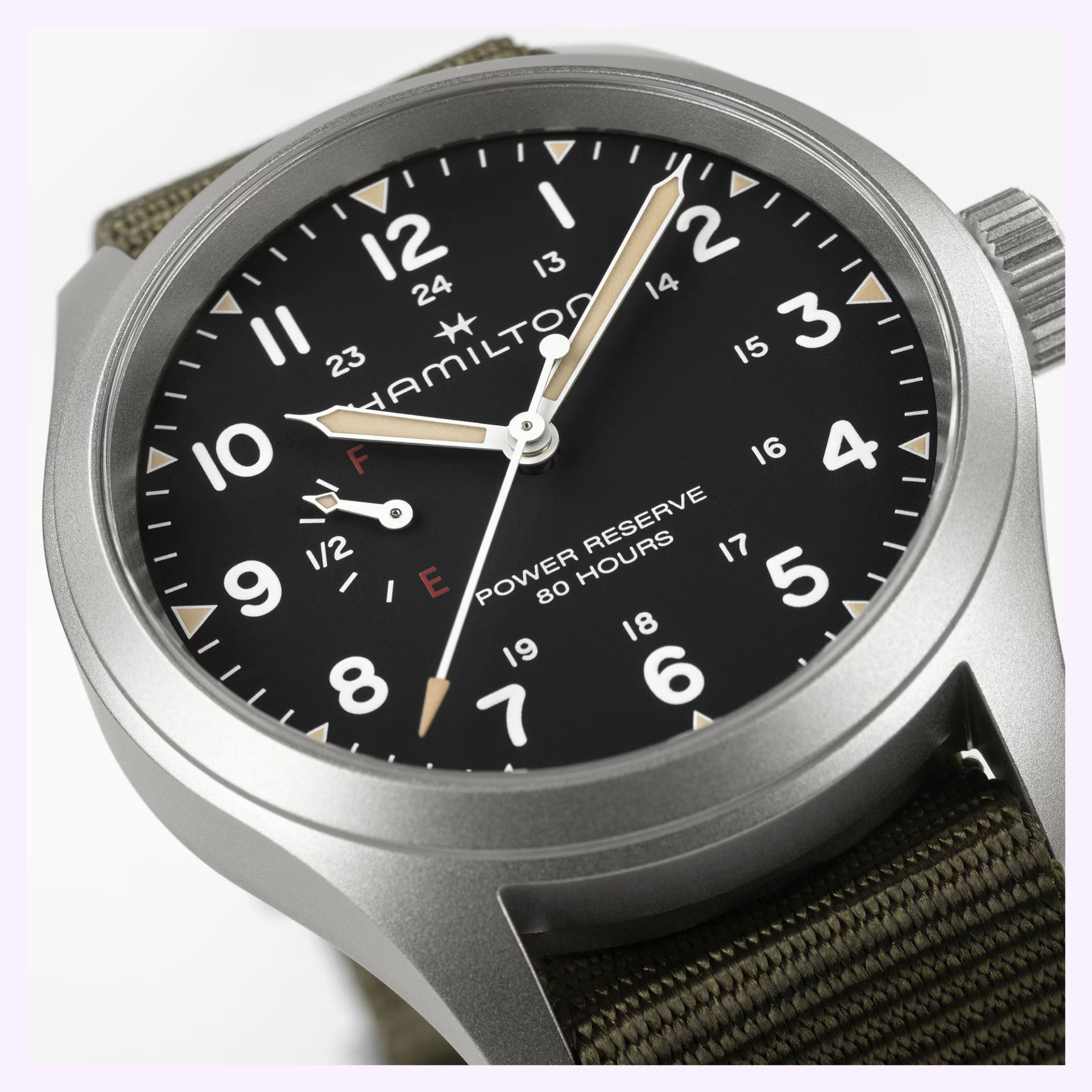 A close-up of the Hamilton Watches Khaki Field Mechanical Power Reserve 40 mm H69509930 shows its black dial, white numerals, beige hands, green fabric strap, 80-hour power reserve, and prominent power reserve indicator.