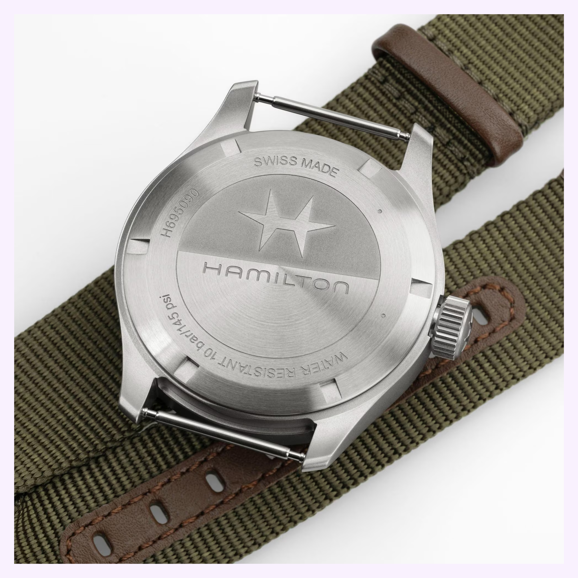 Close-up of the stainless steel back of the Hamilton Watches Khaki Field Mechanical Power Reserve 40 mm H69509930, displaying engraved text and star logo. Features include an 80-hour power reserve and a green strap with brown leather accents.