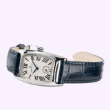 The Hamilton Watches American Classic Boulton Small Second Quartz H13321611 is a women's luxury watch featuring a silver rectangular case with a white dial, Roman numerals, blue hands, and a small seconds subdial at 6 o’clock. Powered by precise Swiss quartz movement and complemented by a dark blue leather strap, this elegant timepiece from Hamilton Watches is beautifully showcased on a light lavender background.
