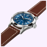 Here's the rewritten sentence using the provided product data: The Hamilton Watches Khaki Field Auto 38 mm H70455540 is an automatic wristwatch crafted from stainless steel, featuring a 38mm case, a bold blue dial with white numerals, a date display, and a brown leather strap accented by white stitching. It is displayed at an angle against a light background.