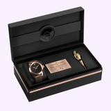 A luxury black gift box featuring the Hamilton Watches Khaki Field Auto The Odyssey Limited Edition H70675530 with a brown strap, a gold figure-shaped pen, and a metallic plaque with engraved text and signature.