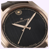 Close-up of the Hamilton Watches Khaki Field Auto The Odyssey Limited Edition H70675530, featuring a brushed black dial, gold ornate hands, star and circle accents, decorative gold border, plus visible Hamilton and Swiss Made branding.
