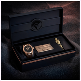 A luxury black box showcases the Hamilton Watches Khaki Field Auto The Odyssey Limited Edition H70675530 with a brown strap, a gold plaque, and a gold Spartan helmet-shaped key—an exclusive tribute from Hamilton Watches.