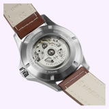 The back of the Hamilton Watches Khaki Field King Day-Date 40mm H64475540 showcases its inner mechanical movement through a transparent stainless steel case back. Paired with light brown and beige leather straps, this automatic timepiece by Hamilton Watches embodies an adventurous spirit and features a practical day-date display.