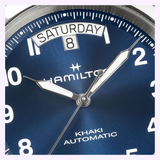 Close-up of a Hamilton Watches Khaki Field King Day-Date 40mm H64475540, featuring a striking blue dial, crisp white hands, and bold numerals. The day-date display at the top shows Saturday and the 8th, while the time reads approximately 10:08:37.