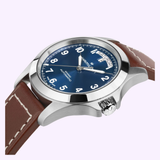 A Hamilton Watches Khaki Field King Day-Date 40mm (H64475540) wristwatch, featuring a stainless steel case, blue dial with white numerals, brown leather strap, and a visible day-date display, is shown on a light background.