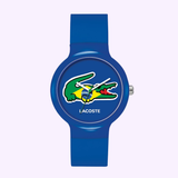 The LACOSTE 2020069 GOA Limited Edition Blue Plastic Strap unisex watch from Lacoste Watches features the crocodile logo with a Brazilian flag on the dial, white hands, "LACOSTE" below it, and a stylish blue plastic strap.