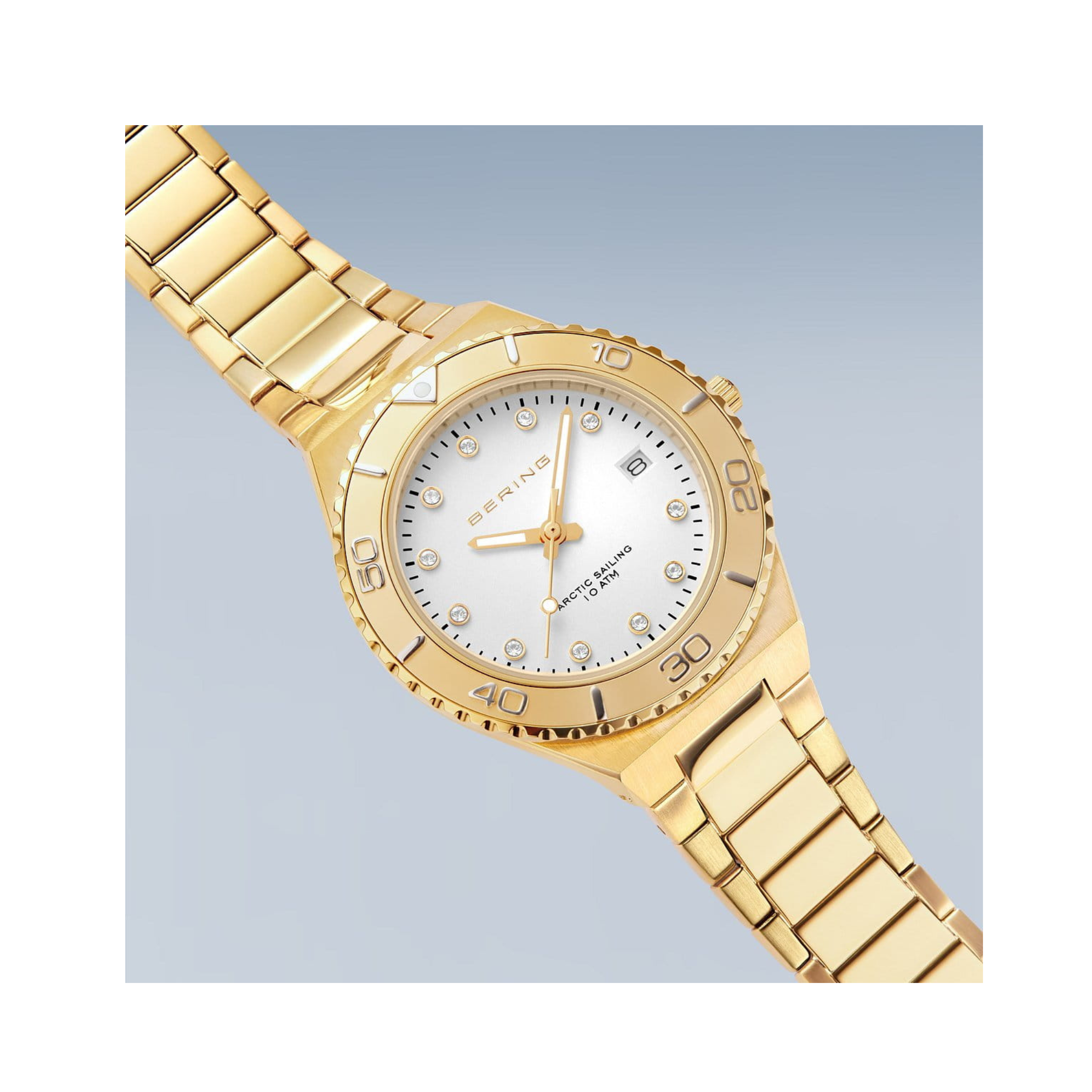 The Bering Watches Classic 18936-734 for women, featuring a polished/brushed gold tone, metal link band, white dial, crystal markers, date display, and gold bezel, embodies Scandinavian minimalism against a light blue background.