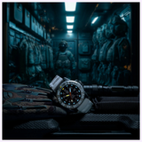 The Luminox Watches MIL-SPEC XL.3359.SET, a military dive watch with 300m water resistance and a rugged strap, rests on gear. A soldier stands in a blue-lit, armored room, enhancing the tactical vibe.