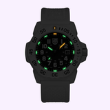The Luminox Watches Navy SEAL 3500 XS.3507.WB features a black design, textured strap, glowing green hour markers, orange-tipped hour hand, luminous numbers, and a date display set against a light background.