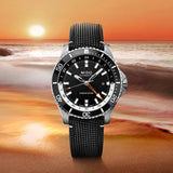 The Mido Watches Ocean Star GMT M0266291705101, featuring a black strap and dial, is showcased against a vivid Miami sunset by the ocean, with gentle waves meeting the shore.