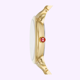 Side view of the MICHELE Watches SEREIN MID MWW21B000160 by Michele Watches (UPC: 99945535944), showcasing its gold round, flat face and a red crown with a white MW logo, set against a pale lavender background.