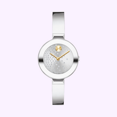 The MOVADO WATCHES BOLD Bangle 3601160 by Movado Watches features a modern silver design, sleek band, minimal face with gold detail at 12 o’clock, and small crystals diagonally on the left. Displayed on a light purple background for added elegance.
