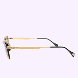 A side view of Maybach Optical sunglasses, model THE WOLF I MG-AB-M09, showcases gold frames with dark lenses and black ear tips, set against a light purple background.