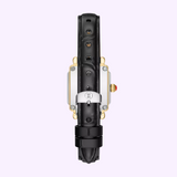 A black leather watch strap with a silver clasp and a gold crown accented by a red tip, displayed from the back against a light purple background, perfectly complements the sophisticated aesthetic of Michele Watches. This elegant strap is specifically designed to fit the Michele Watches Deco Madison Mini MWW06D000179.