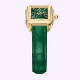 Showcasing the sophisticated style of Michele Watches’ Deco Madison Mini collection, the Michele Watches Deco Madison Mini MWW06D000182 features a square gold-tone case, a green face with Roman numerals, and a dark green leather strap. This elegant timepiece also boasts a crown with a distinctive red accent, all set against a light purple background.