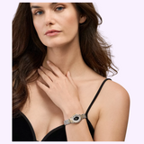 A woman in a black spaghetti strap top displays the Michele Watches Serein Oval Diamond MWW21H000005 by Michele Watches, featuring Swiss movement. Her hand rests near her collarbone as she gazes forward with a neutral expression.