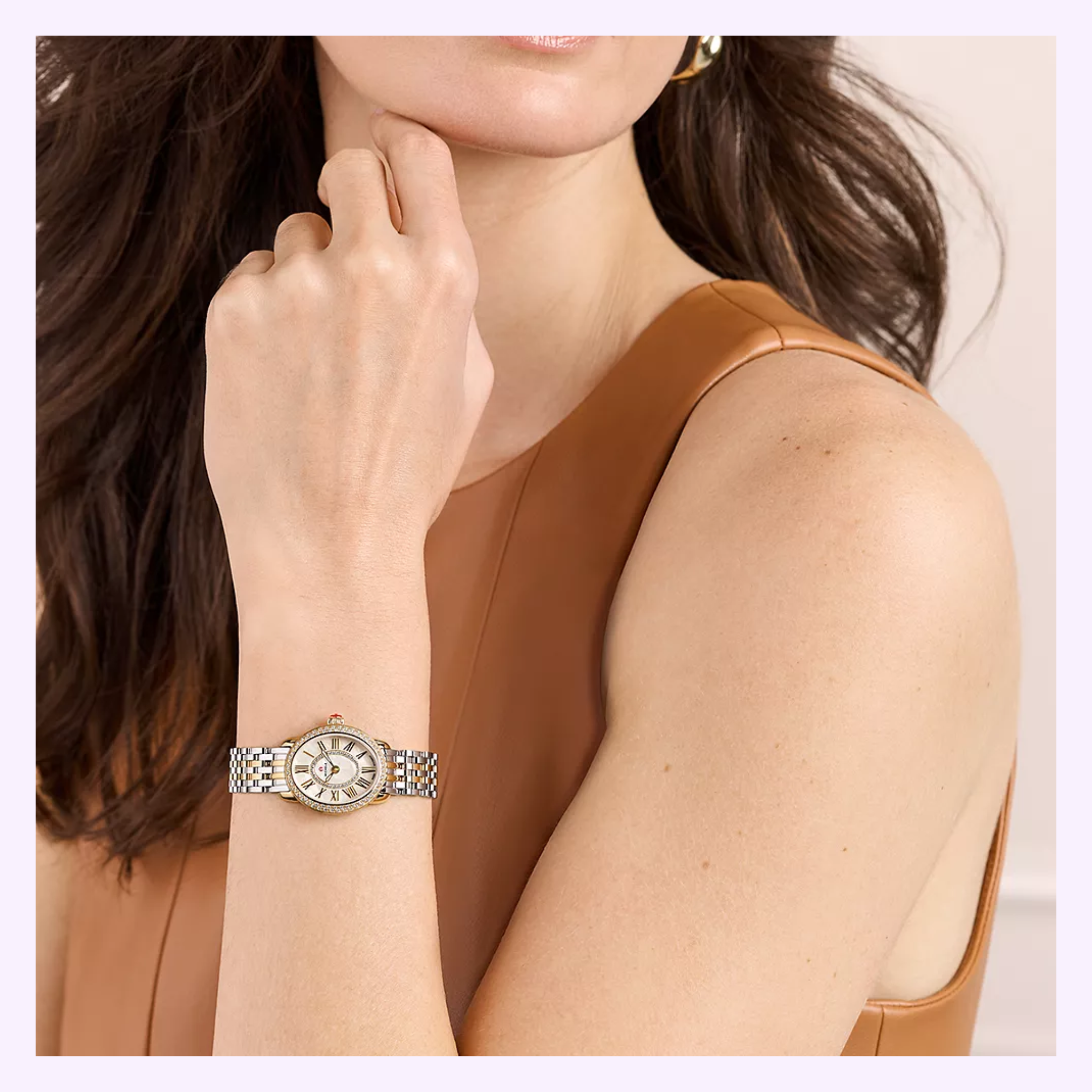 A woman in a sleeveless tan dress rests her chin on her hand, showcasing the Michele Watches Serein Oval Diamond Two-Tone 18K Gold-Plated Watch MWW21H000002 on her wrist.